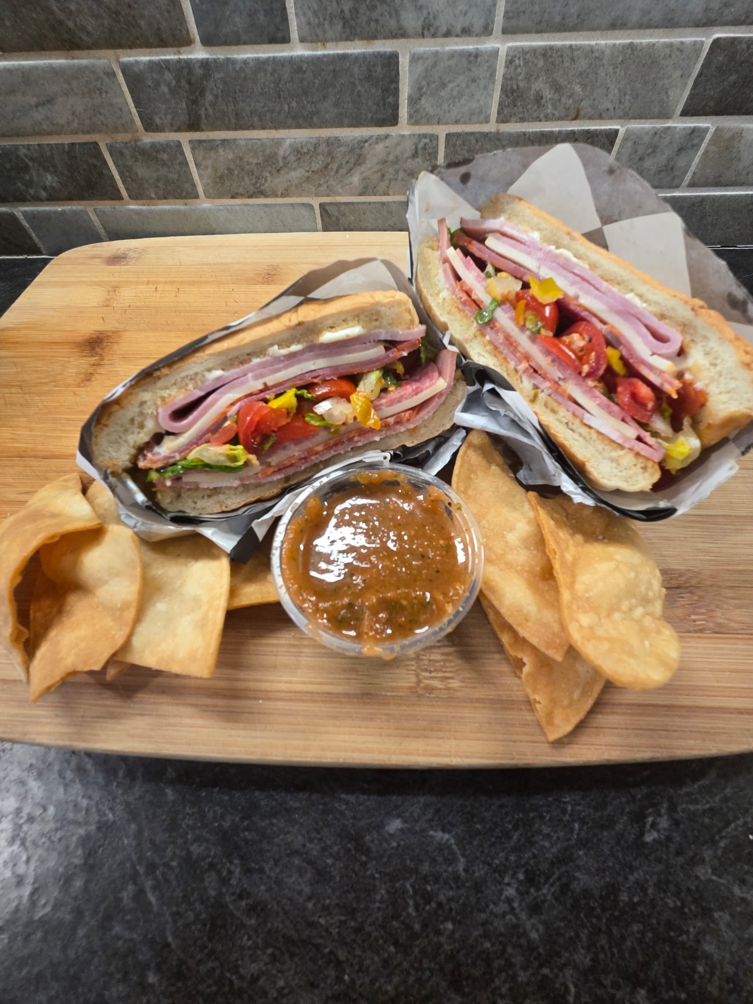 Chicken salad with pita chips and dipping sauce on a wooden board