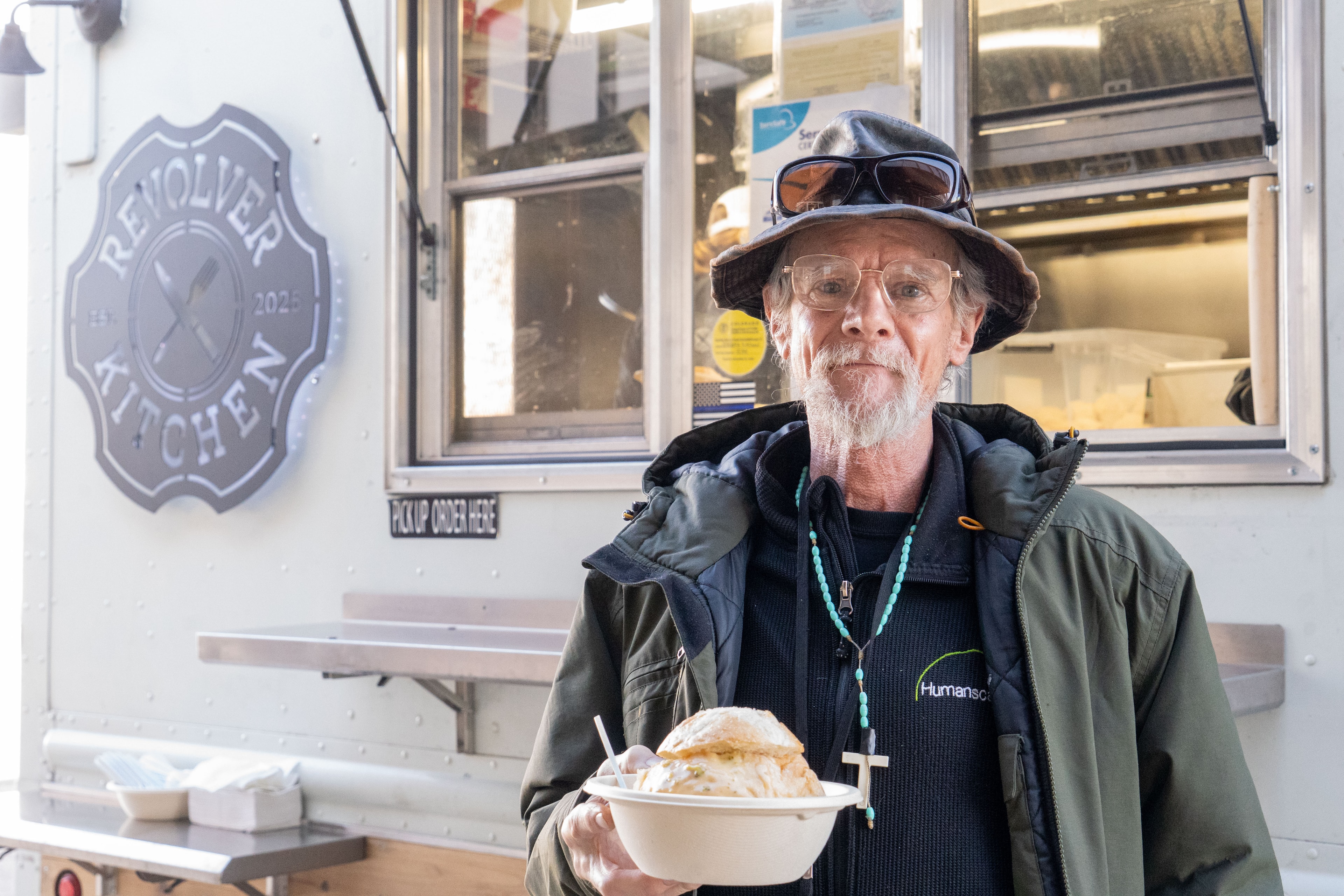 Customer holding a bread bowl in front of the Revolver Kitchen truck