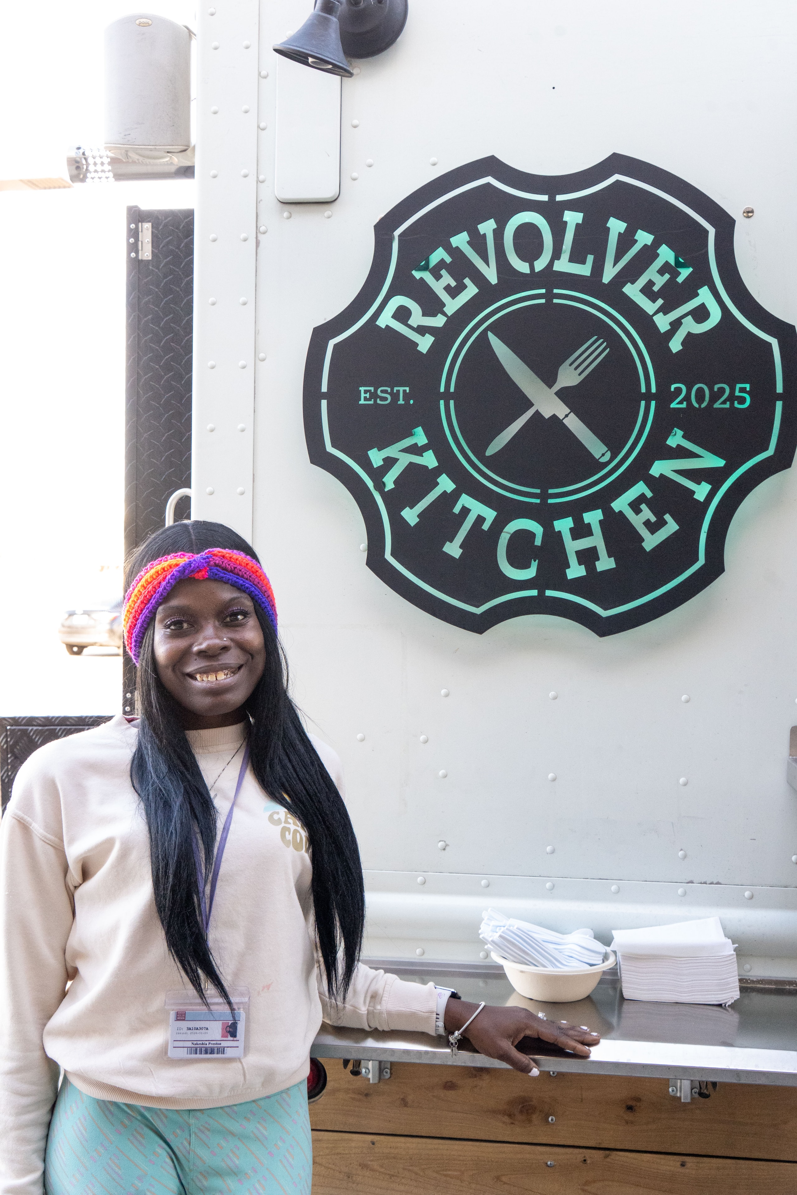 Smiling customer next to the Revolver Kitchen logo on the truck